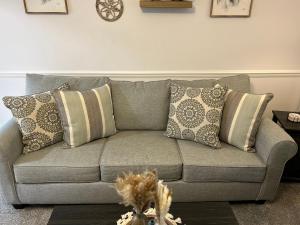 a gray couch with pillows in a living room at Your Weaver Rest Stop on the Ladiga Trail! in Weaver