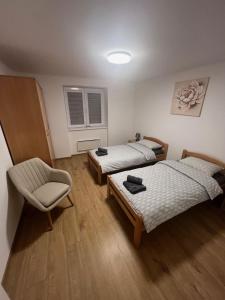 a room with two beds and a chair in it at Apartman Uno in Kikinda