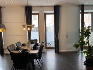 ein Esszimmer mit Tisch und Stühlen und Fenstern in der Unterkunft SYMBIOSE-Ferienwohnung in München