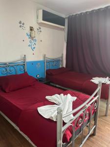 a bedroom with two beds with red sheets at Hostal oasis in Cairo