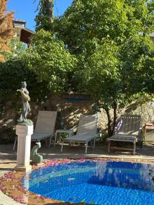 a pool with chairs and a statue next to a fountain at Villa hira in Eski Datca
