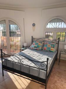 a bed in a bedroom with two large windows at Casa Valdi, fantastic 4 bedroom house with private,heated swimming pool and barbecue in Ciudad Quesada