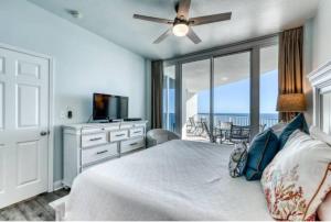 a bedroom with a bed with a ceiling fan and a balcony at Lighthouse 1115 Condo on the beach 3BR 3BA in Gulf Shores +33 photos