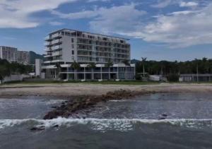 a building on the beach next to a body of water at Beachfront|Pool|Gym Beautiful Studio Zantamar 303D in Cruz de Huanacaxtle