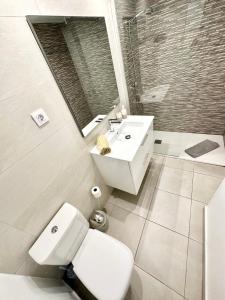 łazienka z toaletą, umywalką i lustrem w obiekcie Chocolate Brownie Piscina, Terraza, Planta baja, parking y WIFI w Corralejo