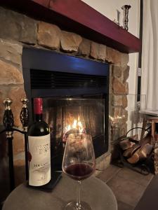 a bottle of wine and a glass of wine in front of a fireplace at La Félicita chalet in Saint Adolphe D'Howard +16 photos