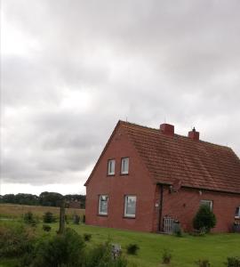 a red brick house on a green field at Landhaus Löwenzahn in Dornum