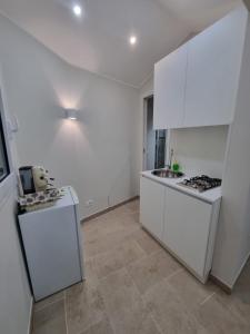 a white kitchen with white cabinets and a sink at La Trinacria casa vacanze in Bronte