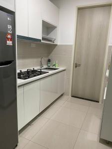 Una cocina con gabinetes blancos y una estufa y una puerta. en Skyhomes KLCC New, en Kuala Lumpur