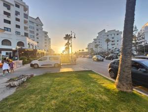 a street with cars parked on a street with palm trees at Luxury Tangier Oceanview Beach Apartment with Balcony, Fast Wi-fi & AC in Tangier