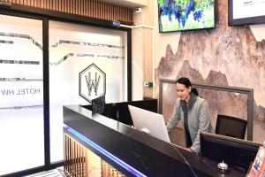 a woman standing at a counter with a laptop at Hotel HW EXPRESS in Santiago