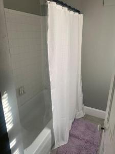 a white shower curtain in a bathroom with a purple rug at Victorian Getaway in Cincinnati +11 photos