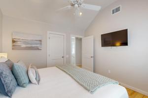 ein weißes Schlafzimmer mit einem Bett und einem Deckenventilator in der Unterkunft Mercer Village at Old Town #3B in Port Aransas