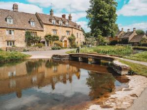 a bridge over a river in a village at Cotswold Dream Getaways in Cirencester