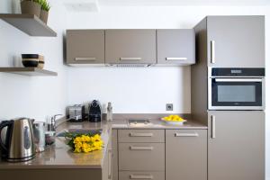 a kitchen with white appliances and yellow flowers on the counter at The Rosebery by Supercity Aparthotels in London