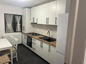 a kitchen with white cabinets and a sink and a table at PremiumSuites in Giurgiu