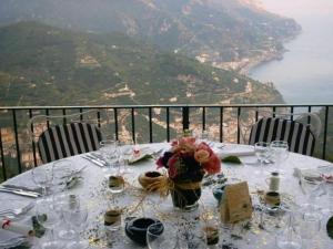 a table with glasses and flowers on it with a view at Hotel Parsifal - Antico Convento del 1288 in Ravello