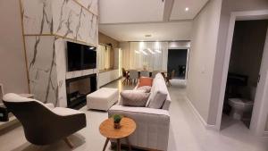 un salon avec un canapé, des chaises et une télévision dans l'établissement Verão Relaxante no Condomínio Las Palmas, à Xangri-lá