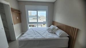 un lit dans une chambre avec une fenêtre dans l'établissement Verão Relaxante no Condomínio Las Palmas, à Xangri-lá