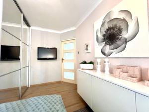 un salon avec une télévision et un tableau de fleurs sur le mur dans l'établissement Comfort Home, à Olsztyn