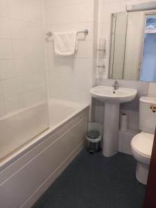 a bathroom with a sink and a tub and a toilet at Sandown Park Lodge in Esher +18 photos