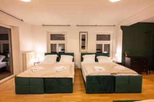 Munich Large Apartment 110 qm, 3 Bedrooms and very Central 1-12 Guests في ميونخ: سريرين في غرفة بسريرين اخضر مصطفي