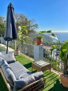 a patio with an umbrella and a couch and a table at SeaHomes Vacations, LA CASA BLUE Mediterranean Lifestyle in Blanes