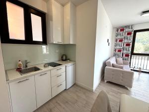 a kitchen with white cabinets and a sink and a chair at Villa Mona 2 in Budva