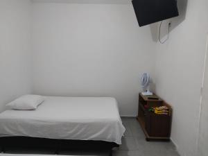a bedroom with a white bed and a night stand at FLAT - primeiro andar - perto do Classic Hall e Centro de Convenções in Recife