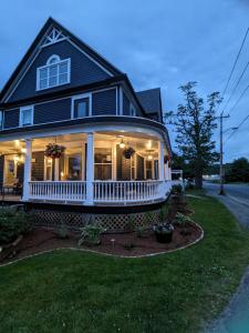 a house with a white porch and a yard at Rose & Thistle B&B Lunenburg in Lunenburg
