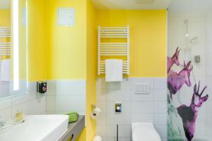ein Badezimmer mit gelben Wänden, einem Waschbecken und einer Badewanne in der Unterkunft Felix Hotel Kaufbeuren in Kaufbeuren