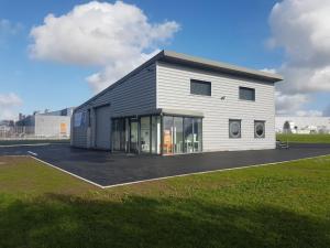 un grand bâtiment blanc avec de grandes fenêtres dans un champ dans l'établissement L'ATELIER 5 couchages, à Malville