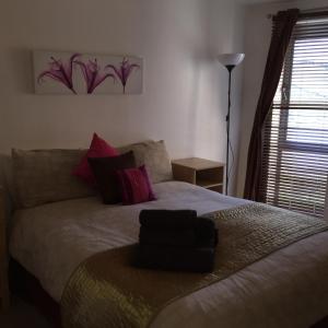 a bedroom with a large bed with pink pillows at Millennium Apartments in Newcastle upon Tyne