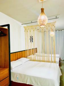 a bedroom with a bed and a chandelier at Noah Hostel & Chale in São Miguel do Gostoso +28 photos