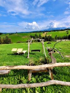 a wooden fence with benches in a field at Willa Widokowa in Bukowina Tatrzańska