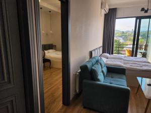 a living room with a blue couch and a bedroom at Seventh Floor Apartment in Kutaisi