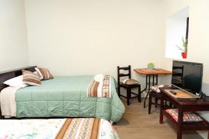 a bedroom with two beds and a desk and a television at Munay Tika house in Cusco