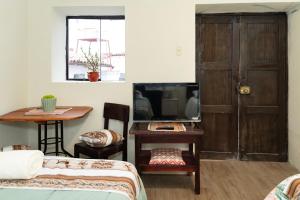 a room with a bed and a tv and a table at Munay Tika house in Cusco