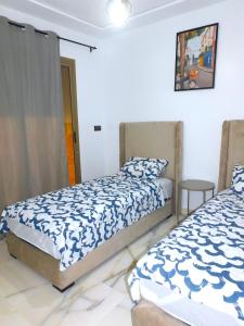 a bedroom with two beds and a table at BB Appartement Cosy clim wifi 5 min de la Plage in Saidia 