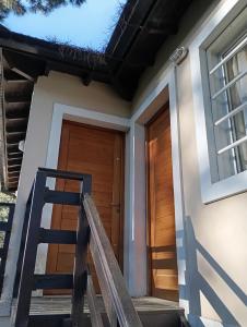 a house with a wooden door and a staircase at Departamentos Ojos del Alma in Valeria del Mar
