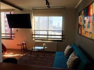 un salon avec un canapé bleu et une télévision dans l'établissement Bello y acogedor dpto cerca metro Baquedano 1303, à Santiago