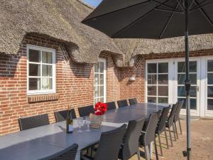 een lange tafel met stoelen en een parasol bij 4 star holiday home in Ulfborg in Ulfborg