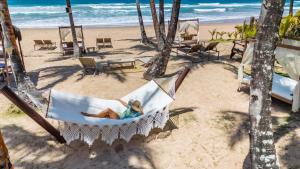 a woman laying in a hammock on the beach at Rumah Pousada in Barra Grande
