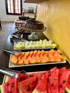Un bufé con varios platos de fruta y un pastel en Pousada Puerta Del Sol Rio das Ostras, en Rio das Ostras