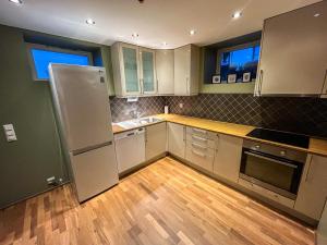 a kitchen with white cabinets and a wooden floor at Two-Bedroom City Apartment with Fire Place, Free Parking and Fjordview Terrace - Calm and Central in Ålesund