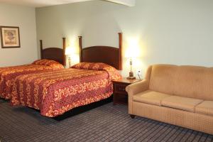 a hotel room with two beds and a chair at American Inn & Suites in Paris