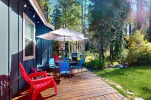 a deck with a table and chairs and an umbrella at Homewood Cabin Among the Pines in Homewood