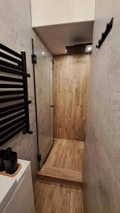 a bathroom with a shower with a wooden floor at Cherry Apartments- CHILL in Wałbrzych +25 photos