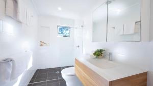 a white bathroom with a sink and a toilet at Buwarla House in Currarong