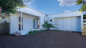 ein weißes Gebäude mit einer Palme davor in der Unterkunft Buwarla House in Currarong